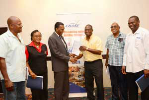 CHASE CEO, Billy Heaven hands a fully executed copy of the construction contract to Douglas Bowes of Otiga Engineering after the signing. Looking on are (l-r):Basil Bowes of Bajad Limited, Rosemarie Houghton representing C.P. Specialists Limited, Neville Diaram of N.R. Diaram Construction and Devon Richards of RICAM Construction.