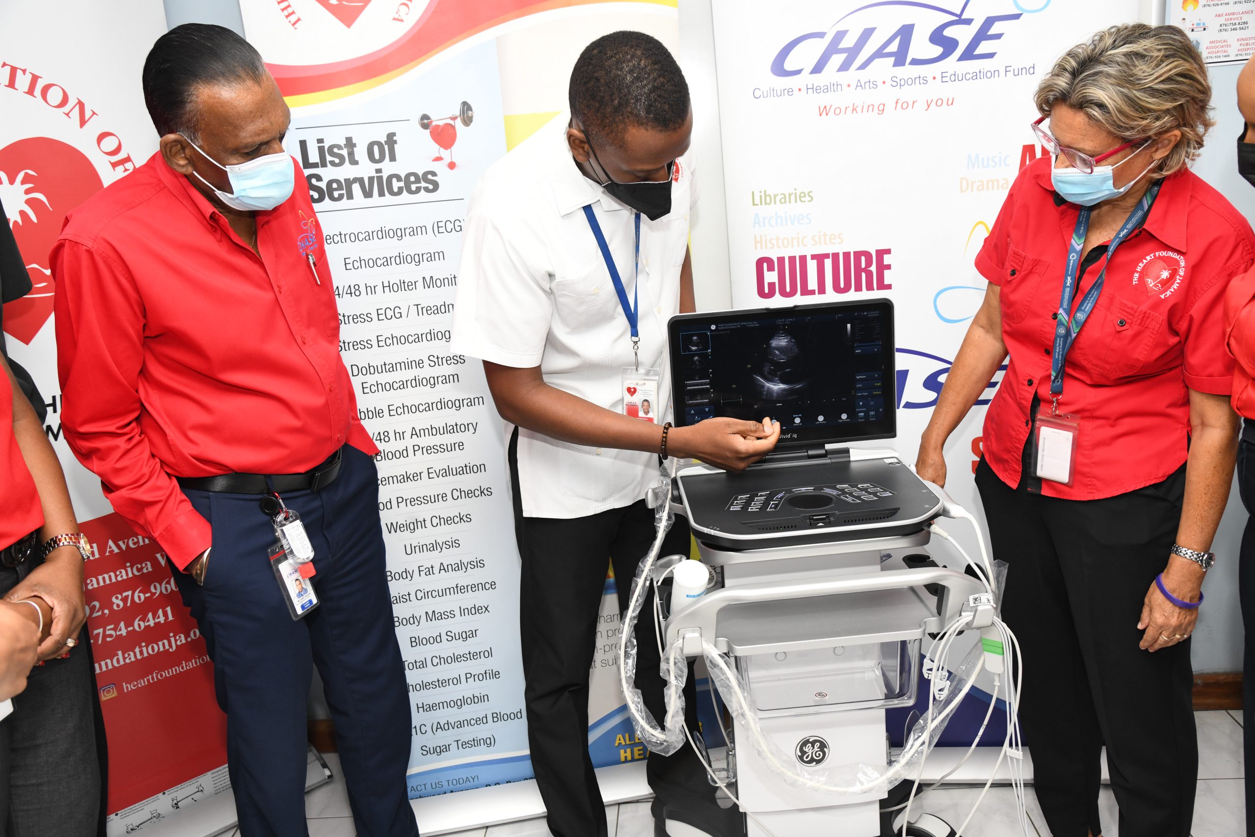 Mr. Carlisle Richardson, Cardiovascular Technician, HFJ, highlights features of the echocardiogram machine to CEO of the Culture, Health, Arts, Sports and Education (CHASE) Fund, Wilford 'Billy' Heaven and Executive Director of the Heart Foundation of Jamaica (HFJ), Deborah Chen. The ECG machine valued at $9 million was donated to the HFJ by the CHASE Fund.