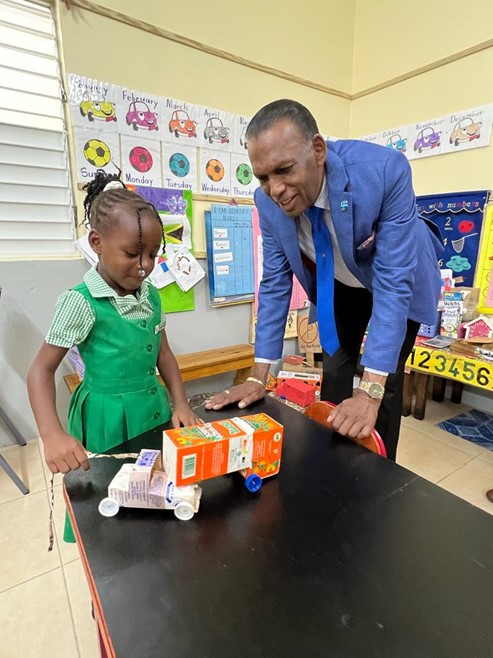CHASE CEO, W. Billy Heaven admires the truck made from juice boxes being shown to him by Savanna La Mar Infant School student, Leana Barker.