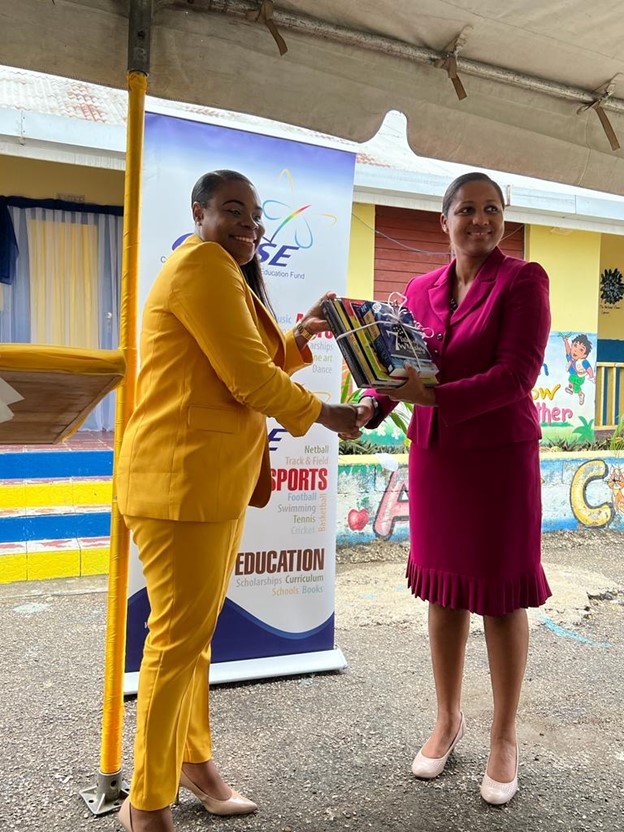 Latoya Foster, CHASE Fund Project Manager (right), presents a number of books to Praise Thompson-Brown, Principal of the Savanna La Mar Infant School during the opening of the new block built by the CHASE Fund. The Fund has supported the publication of over 100 books since its inception.