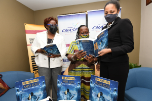 Latoya Aquart-Foster, Project Manager, CHASE Fund (right), looks through the book, “One 100+ Voices for Miss Lou” with Prof. Opal Palmer Adisa, the editor of the anthology and Nadine Buckland, Rights and Permissions/Finance Manager, University of the West Indies Press.